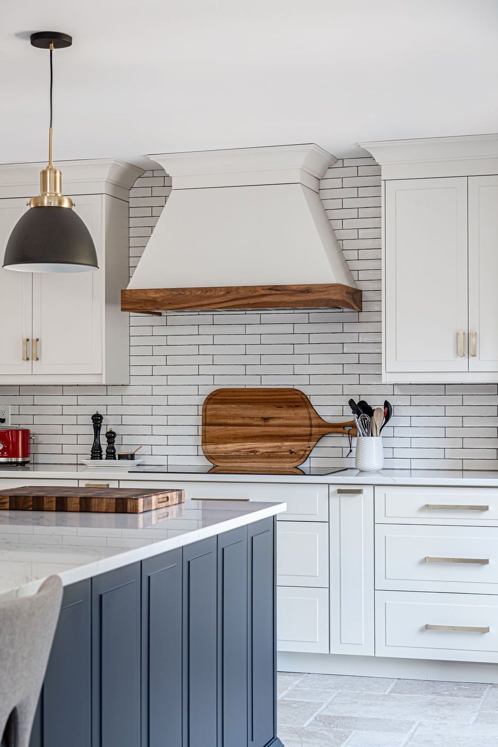 A kitchen with white cabinets and a wooden cutting board on the counter.