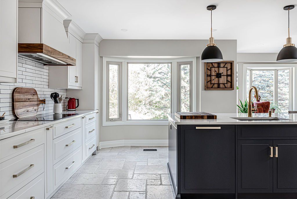 A kitchen with white cabinets , a black island , a sink , and a large window.