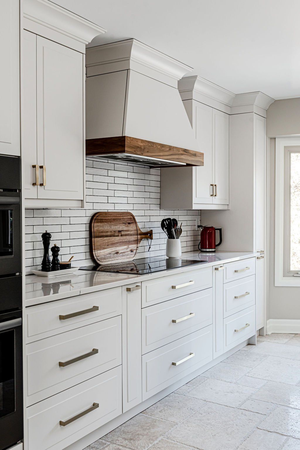 A kitchen with white cabinets and a wooden hood.