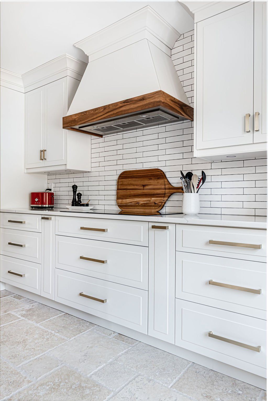 A kitchen with white cabinets and a wooden cutting board on the counter.