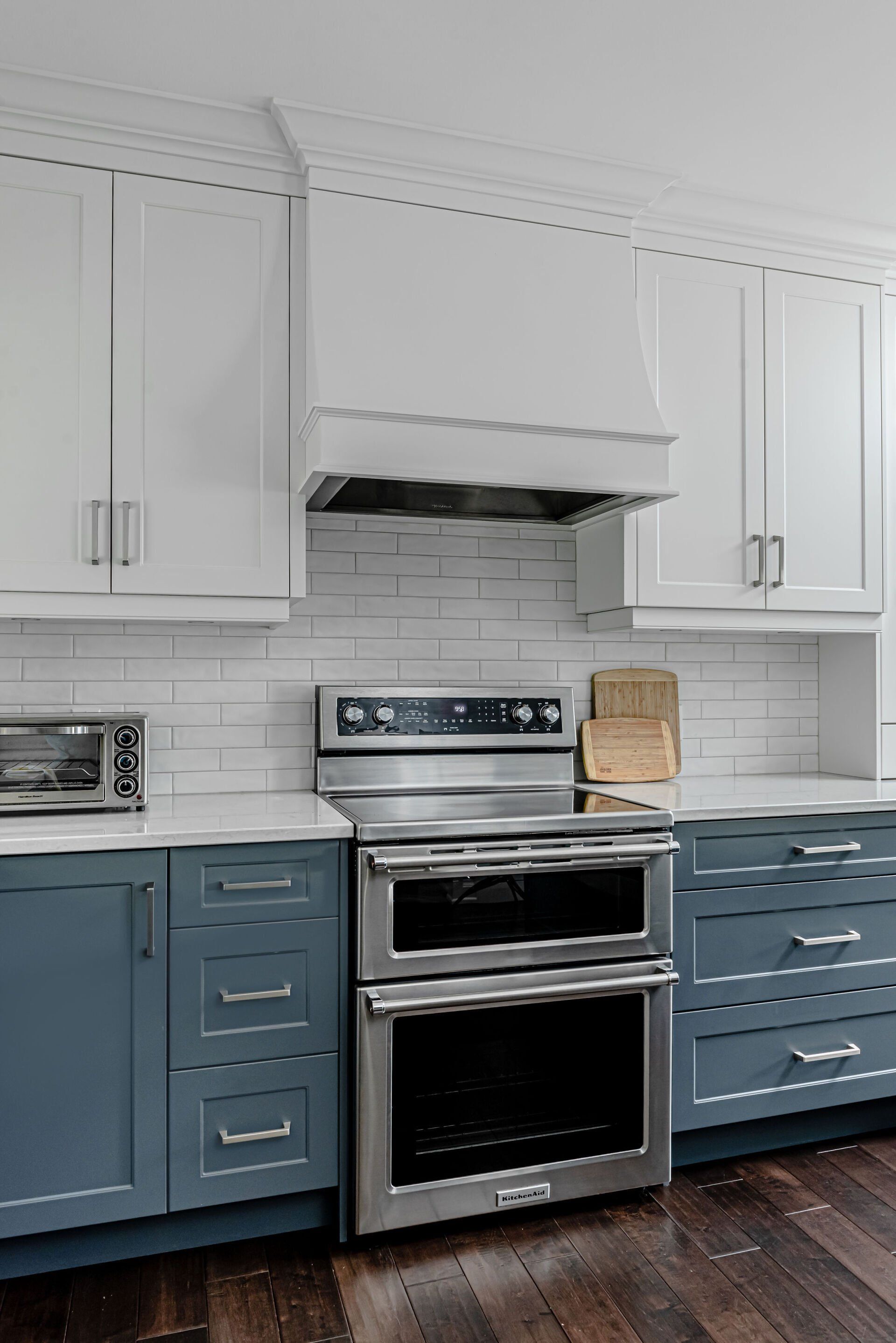 A kitchen with blue cabinets , a stove , and a microwave.