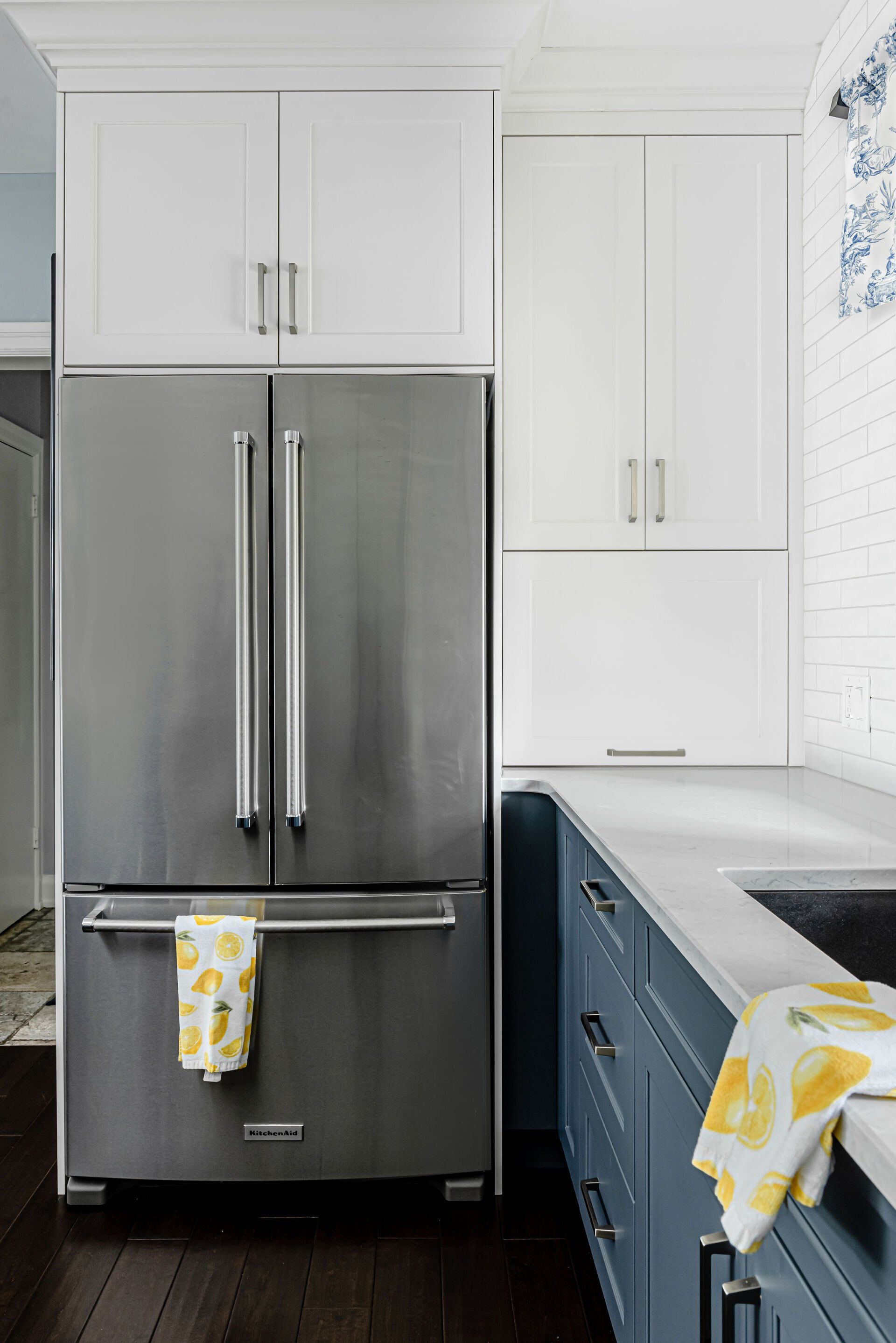 A stainless steel refrigerator is sitting in a kitchen next to a sink.