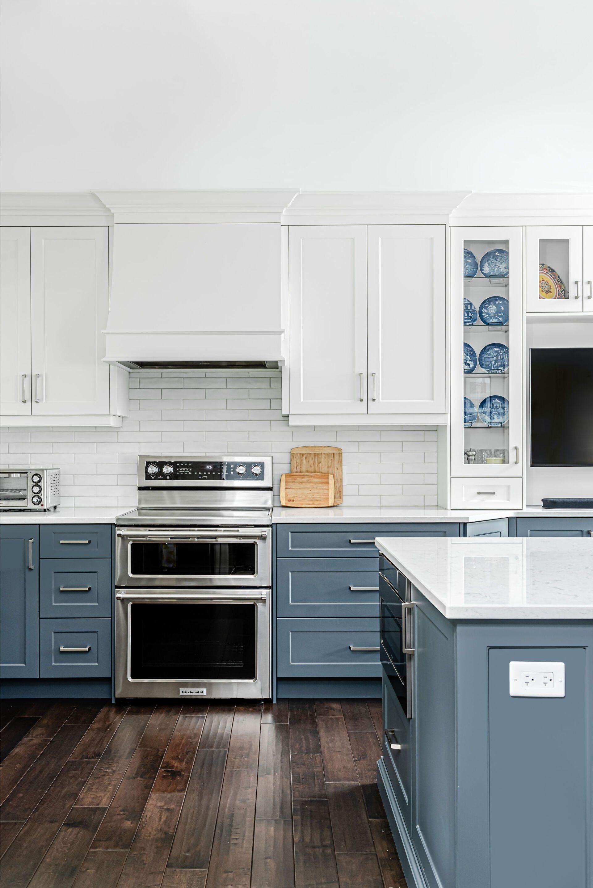 A kitchen with blue cabinets , white cabinets and stainless steel appliances.