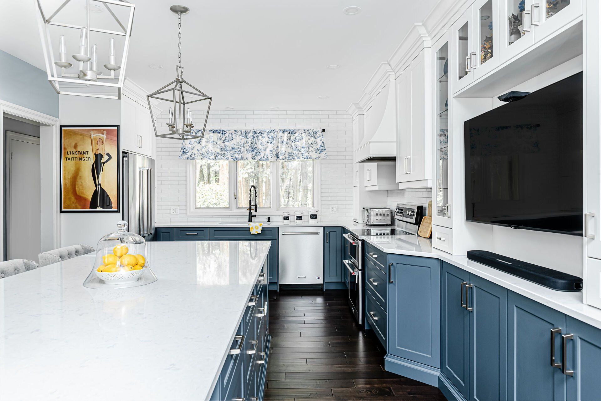 A kitchen with blue cabinets and a flat screen tv on the wall.