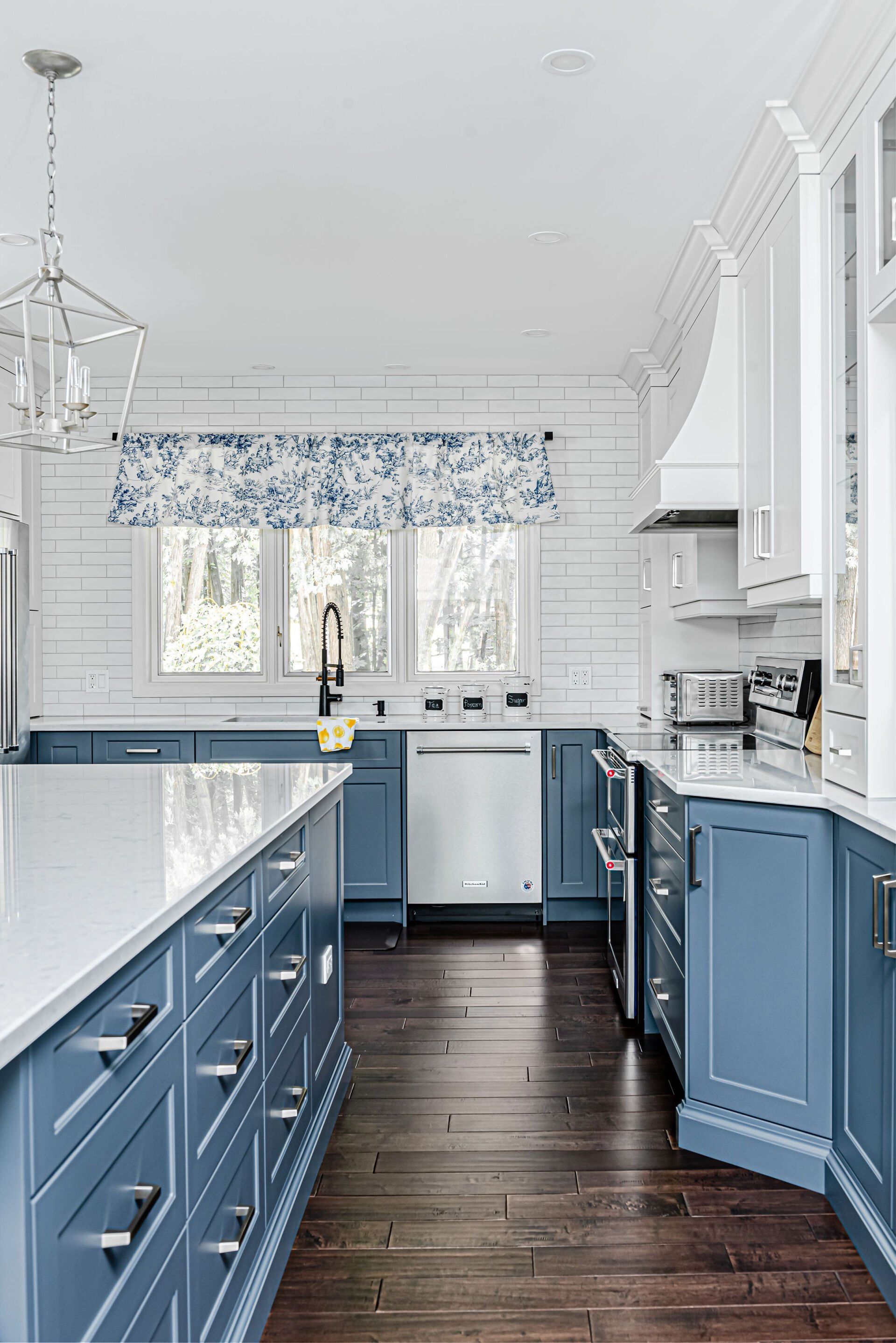 A kitchen with blue cabinets and white counter tops.