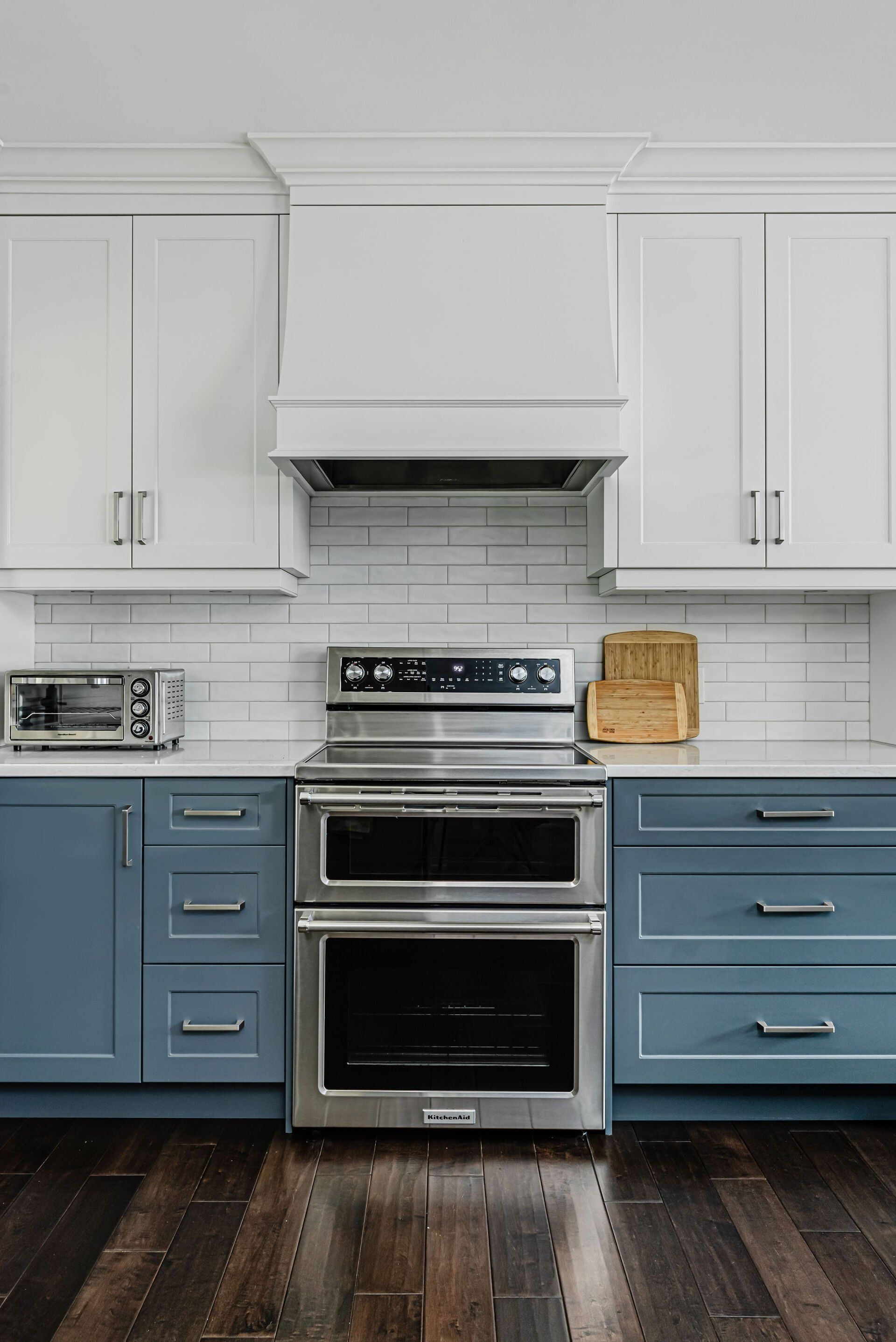 A kitchen with white cabinets and blue drawers and a stove and oven.