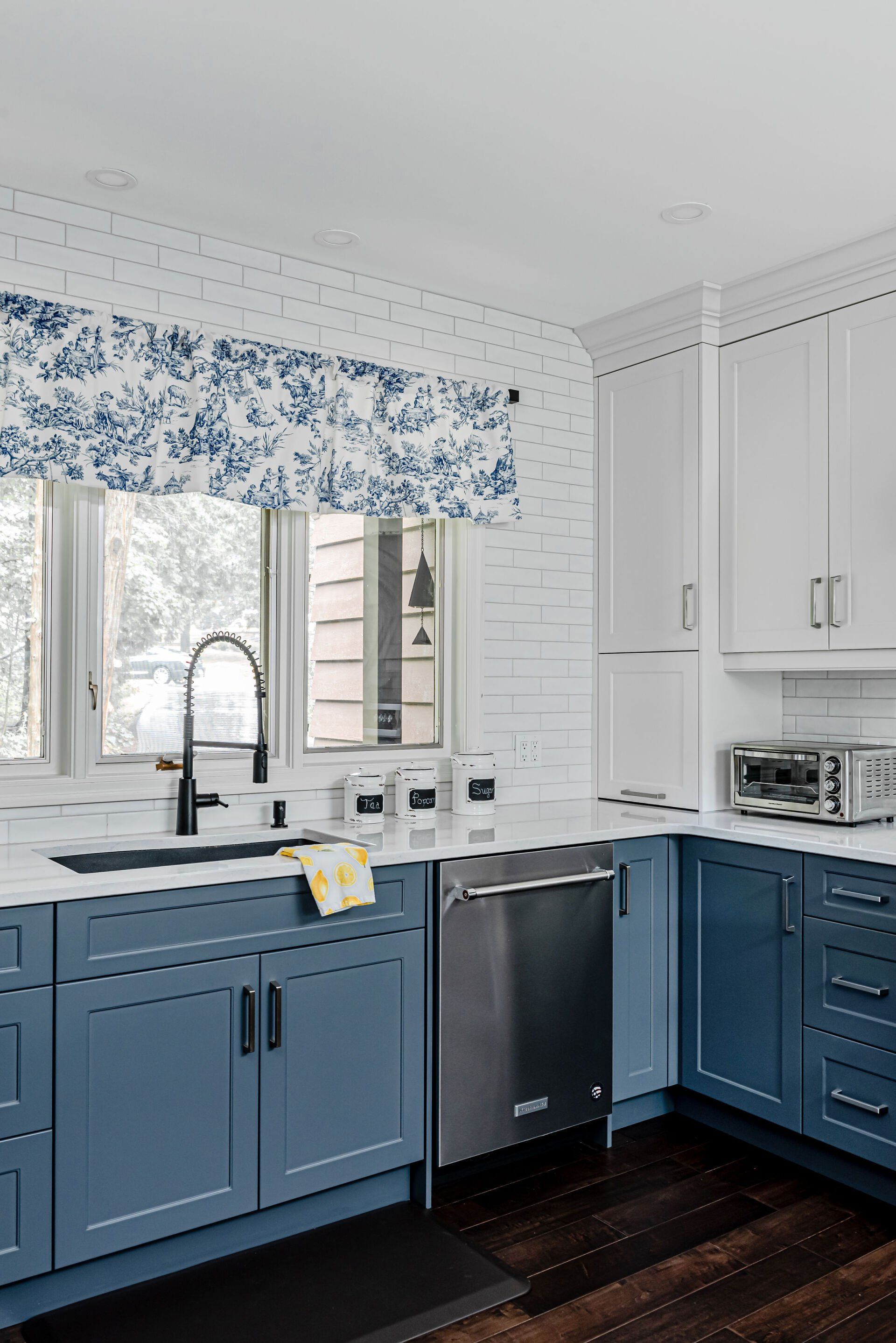 A kitchen with blue cabinets , white cabinets , a sink , and a dishwasher.
