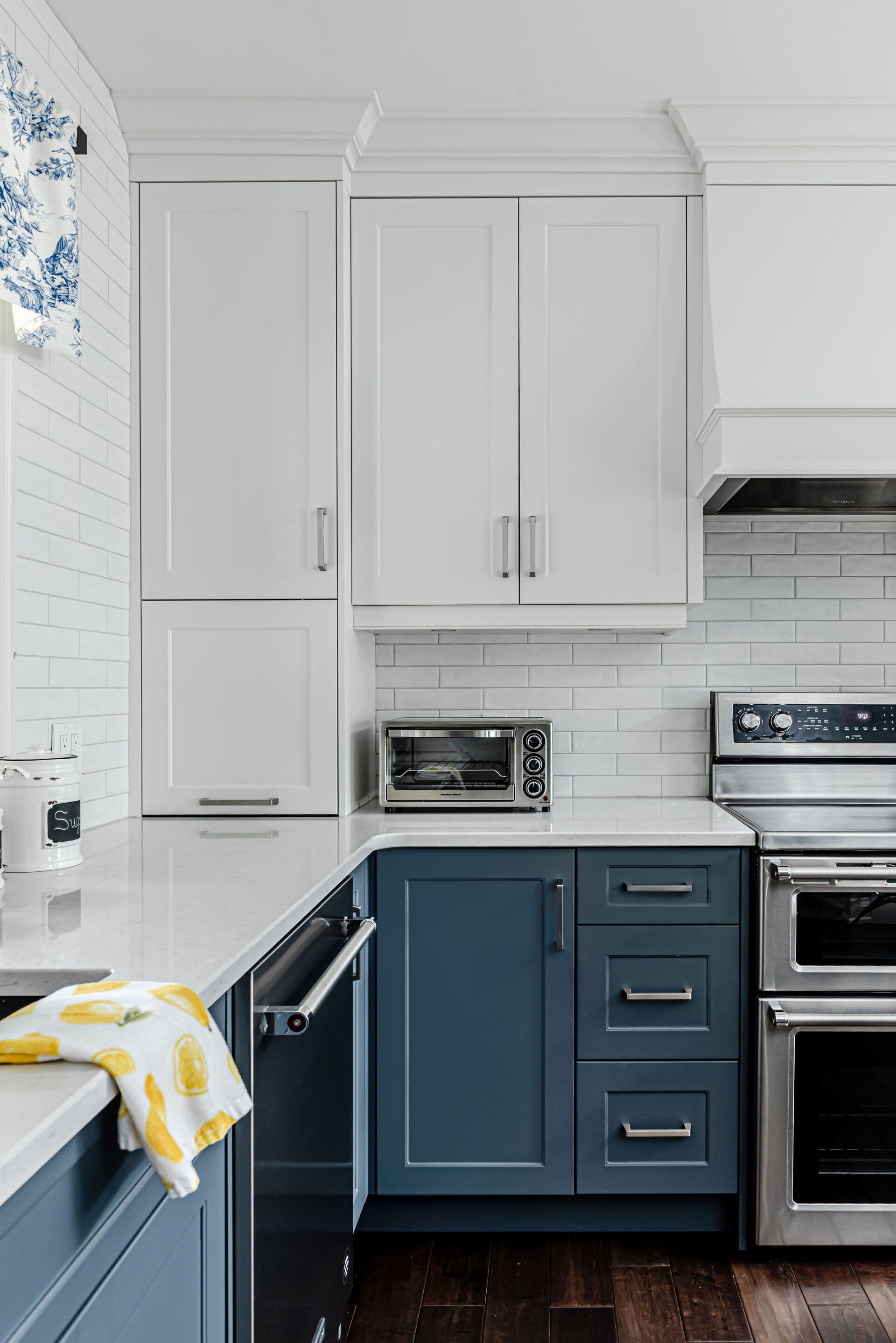 A kitchen with blue cabinets , white cabinets , stainless steel appliances and a toaster oven.