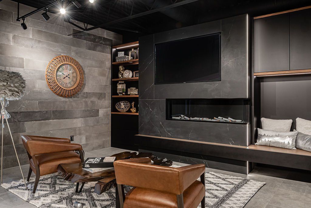 A living room with a fireplace , chairs , a clock and a flat screen tv.