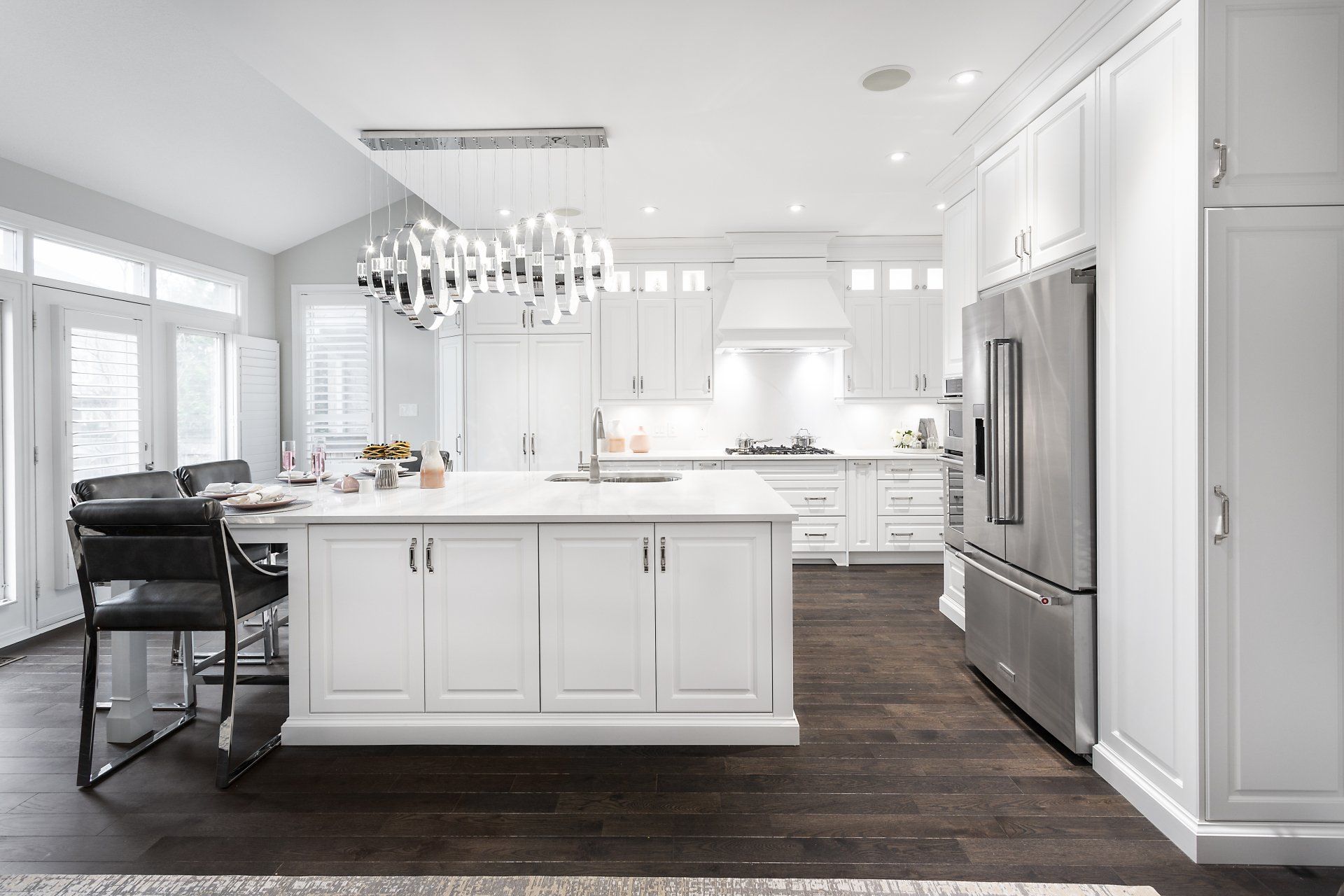 A kitchen with white cabinets and stainless steel appliances and a large island in the middle.