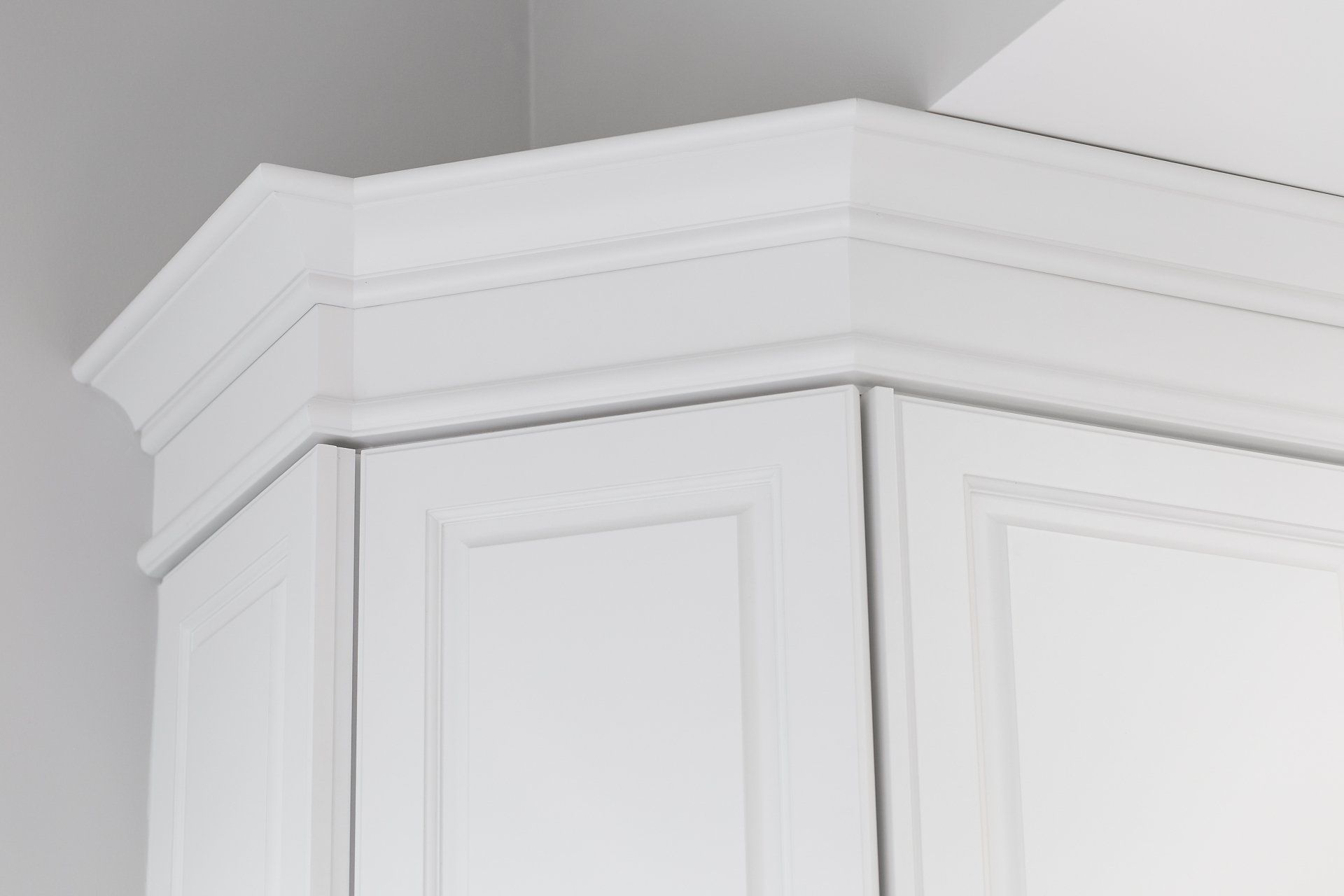 A close up of a white cabinet with a molding on top of it.