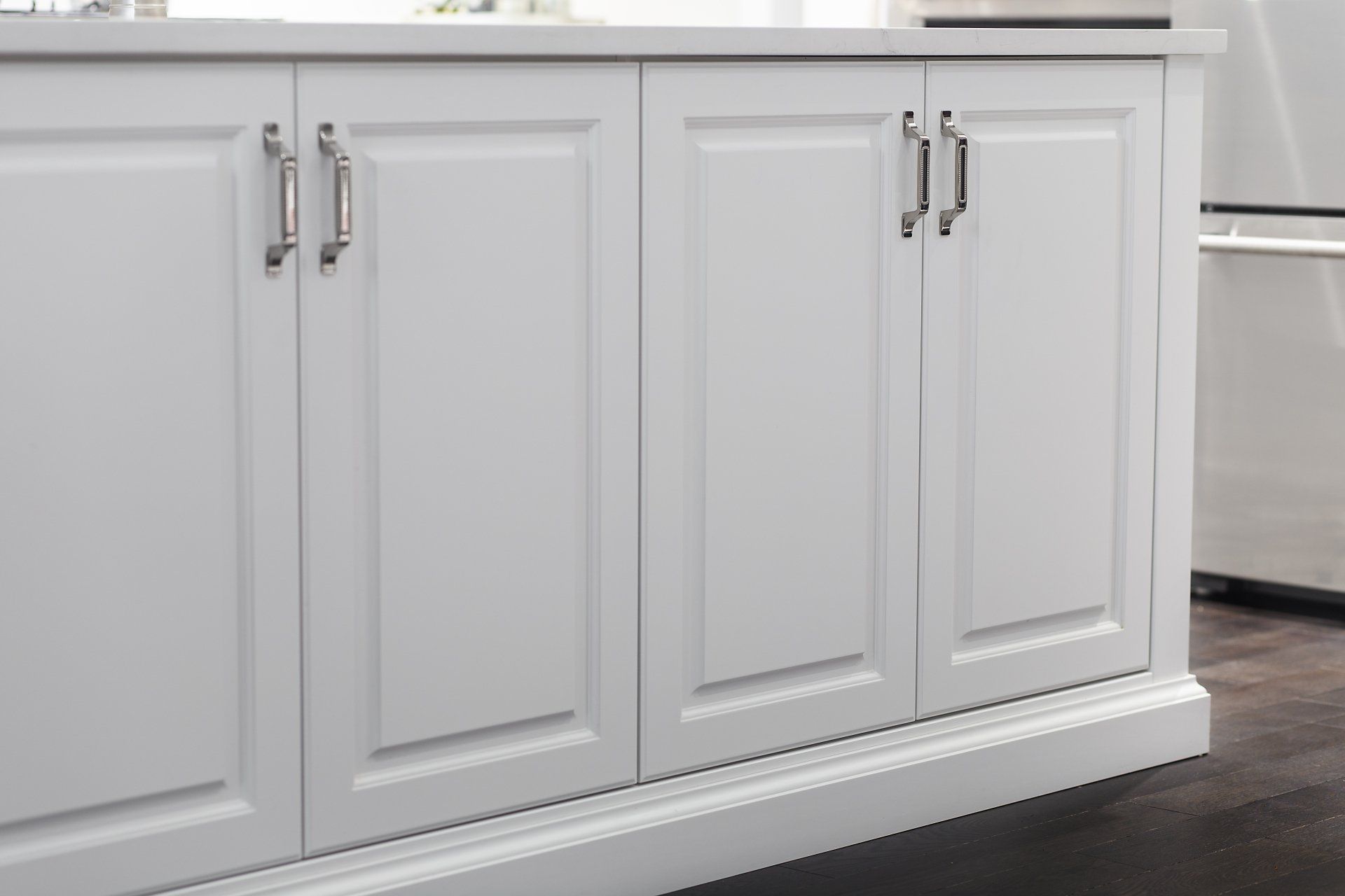 A kitchen with white cabinets and a stainless steel refrigerator.