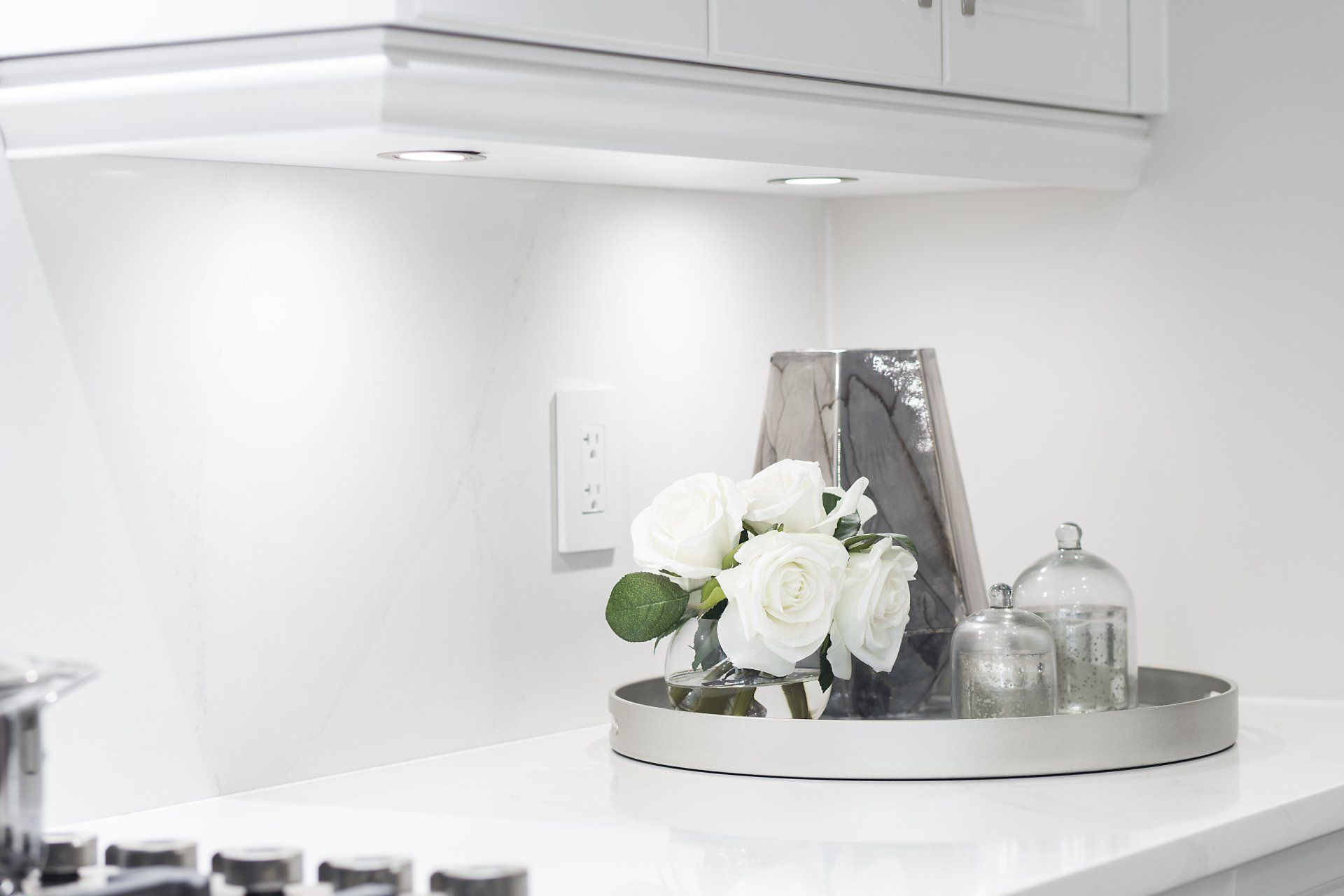 A kitchen counter with a tray of flowers and a picture on it.