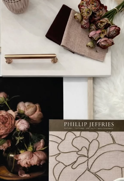 Flat-lay of fabric swatches and floral samples on a white table with a brass handle and design booklet.