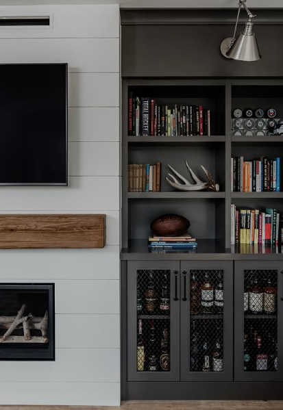 Modern living room with wall-mounted TV, fireplace, and built-in bookshelf cabinet with books and decor