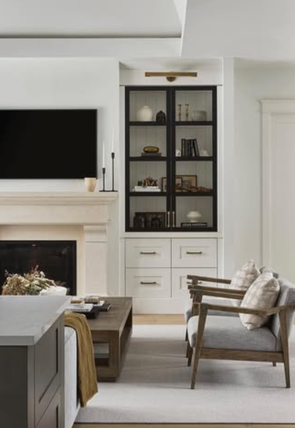 Bright living room with a fireplace, built-in shelves, and two gray chairs by a coffee table.