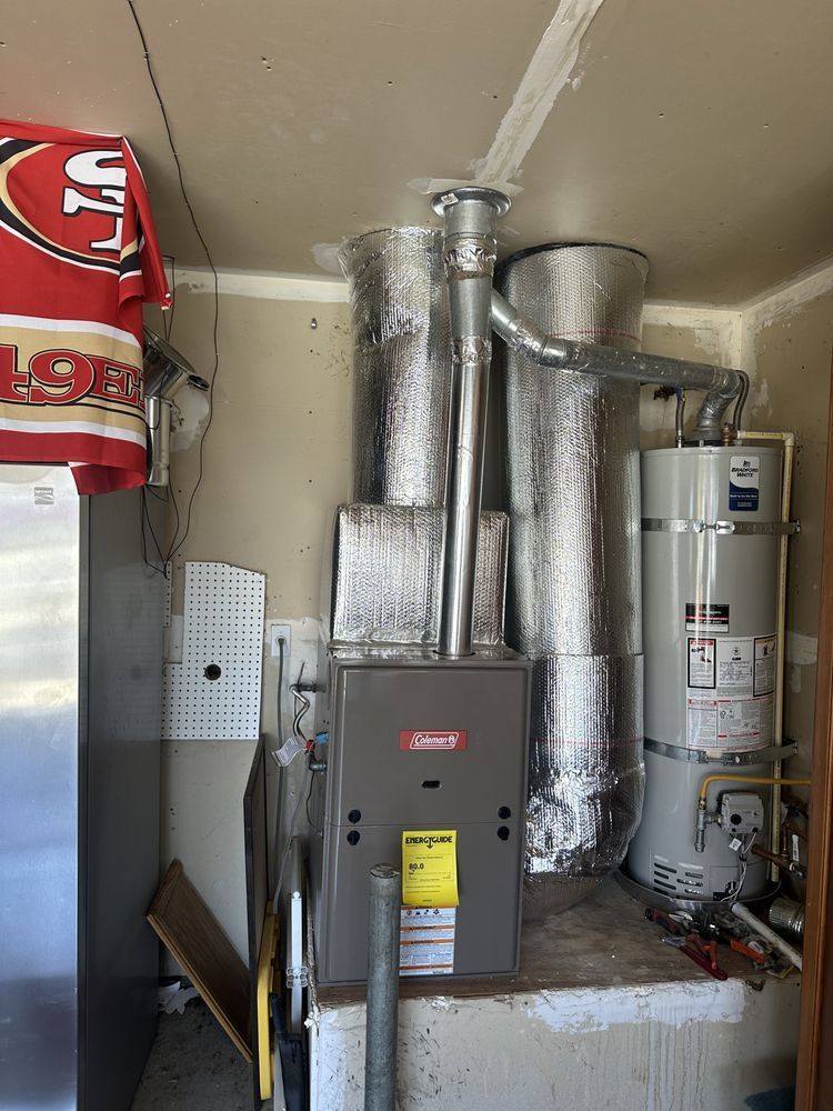 Utility room with a furnace and water heater beside silver insulated ductwork and plumbing tanks.