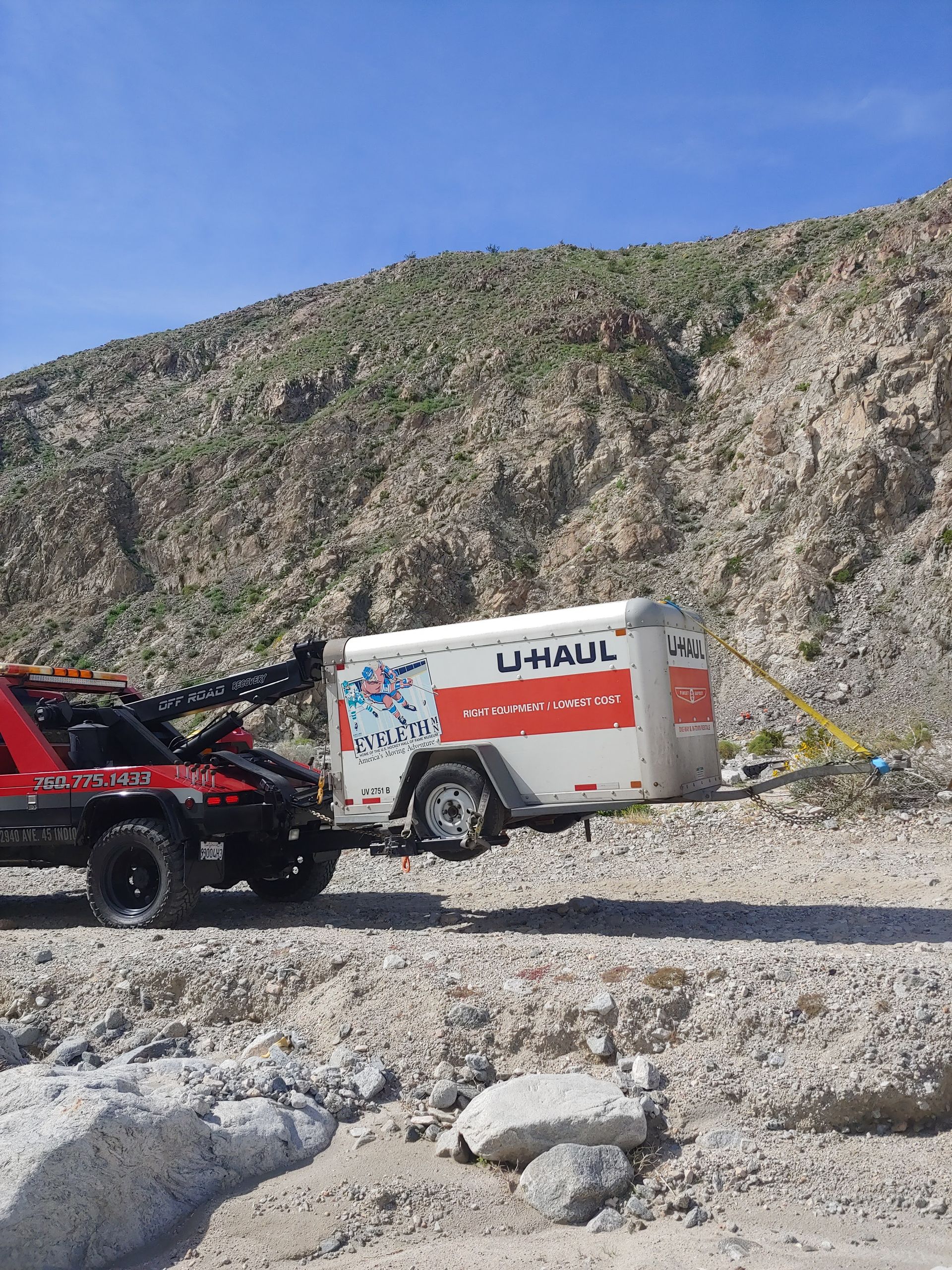 A uhaul trailer is being towed by a tow truck