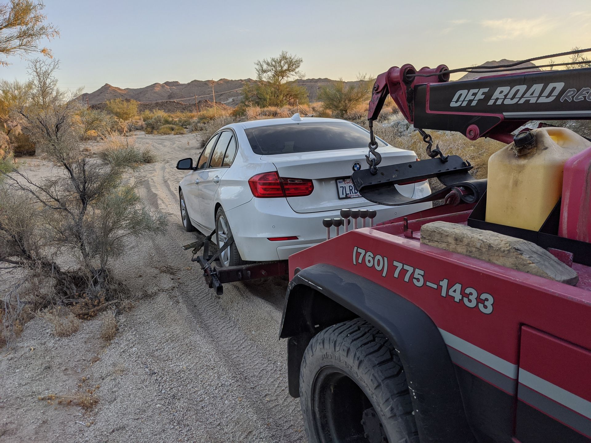 A white car is being towed by a tow truck.