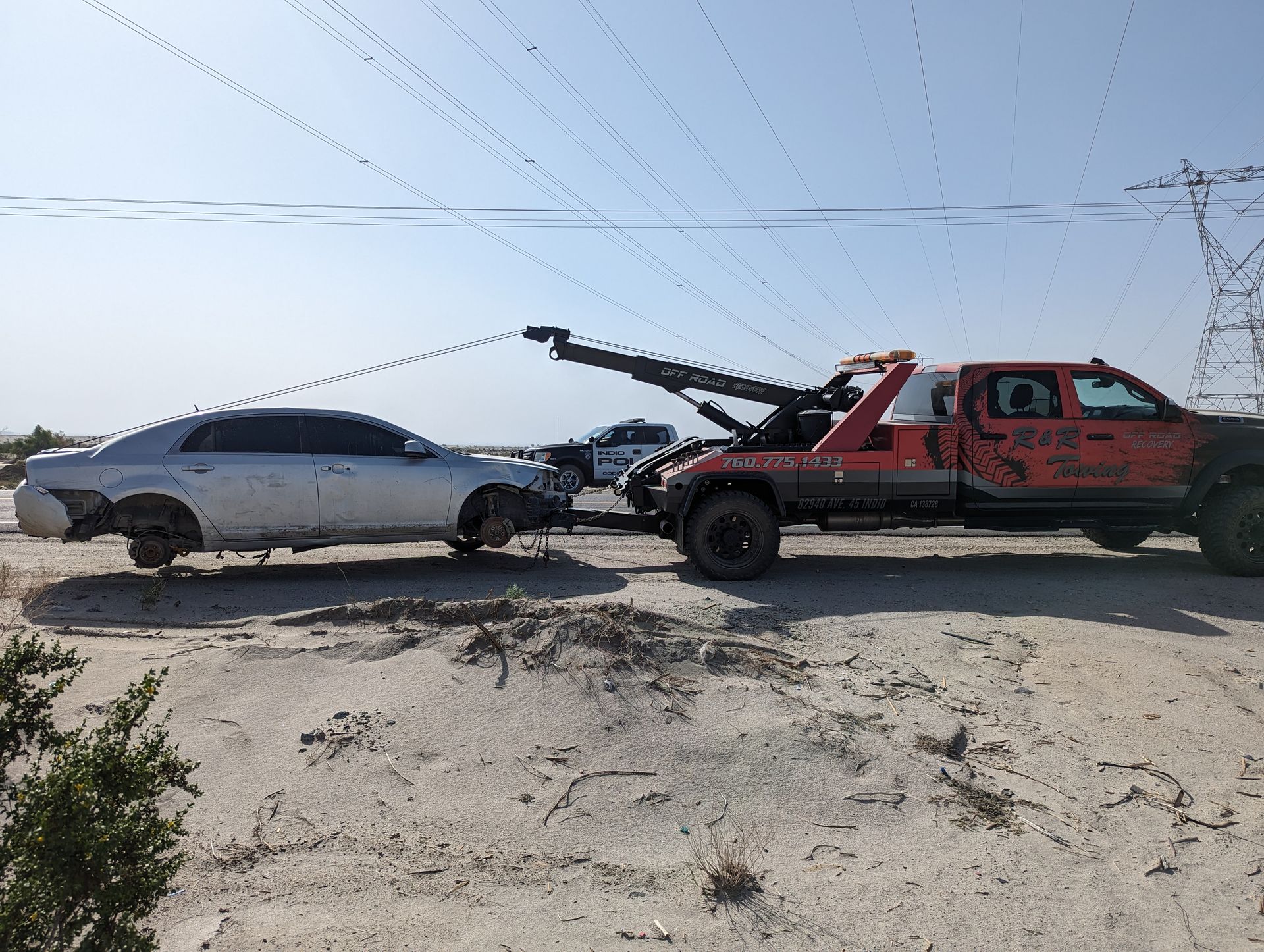 A tow truck is towing a car in the desert.