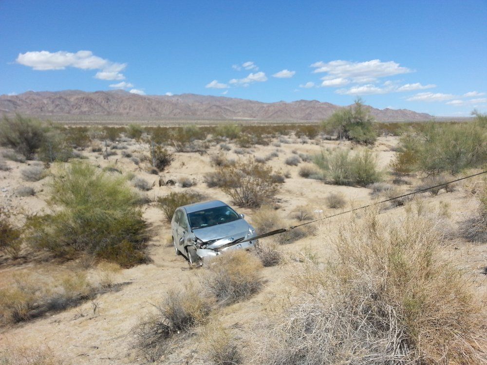 A car is stuck in the desert with mountains in the background