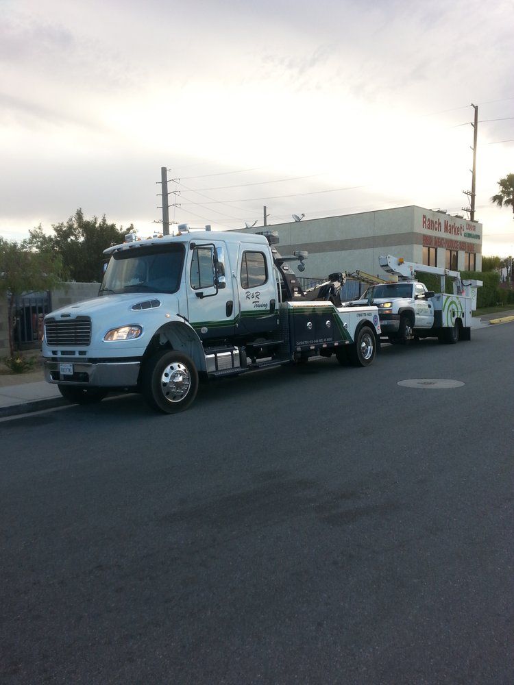 A row of tow trucks are parked on the side of the road
