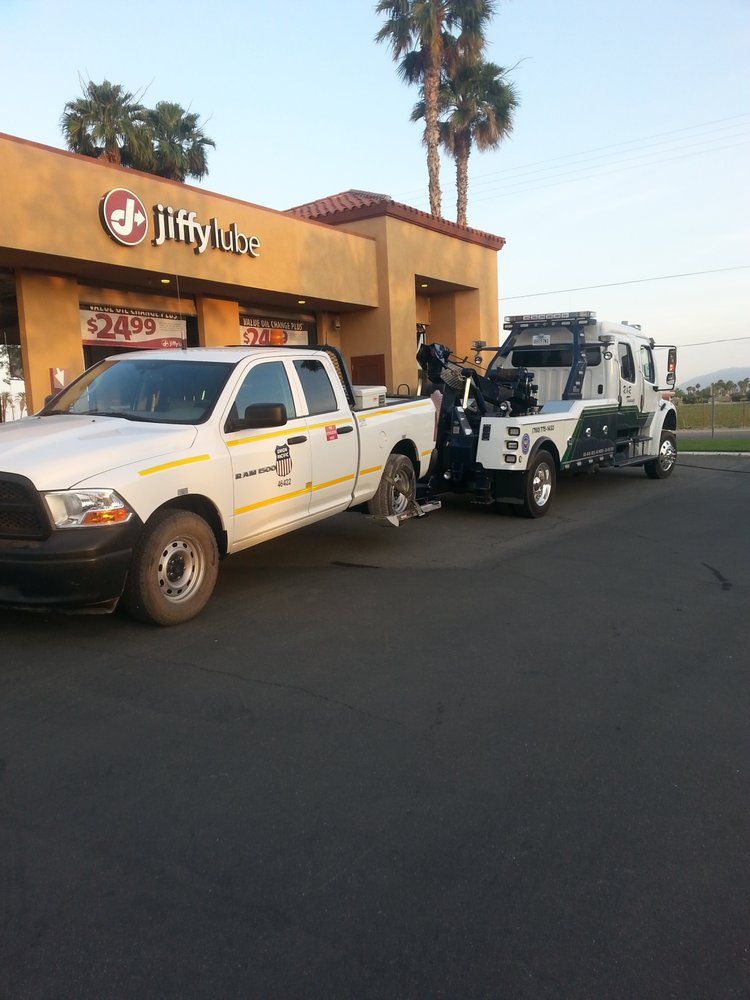 A tow truck is parked in front of a jiffy lube restaurant
