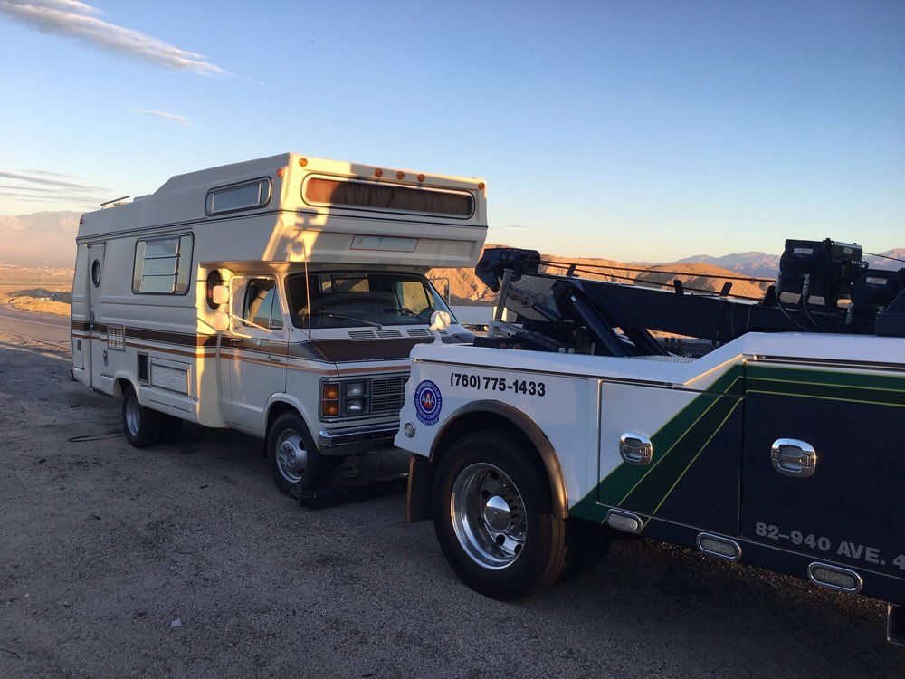 A camper is being towed by a tow truck.