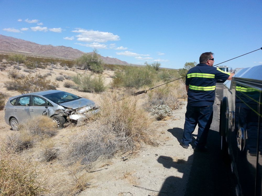 A man is towing a car in the desert