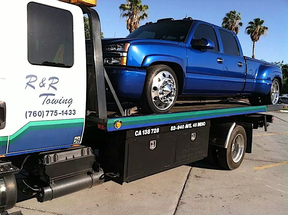 A blue truck is on the back of a towing truck