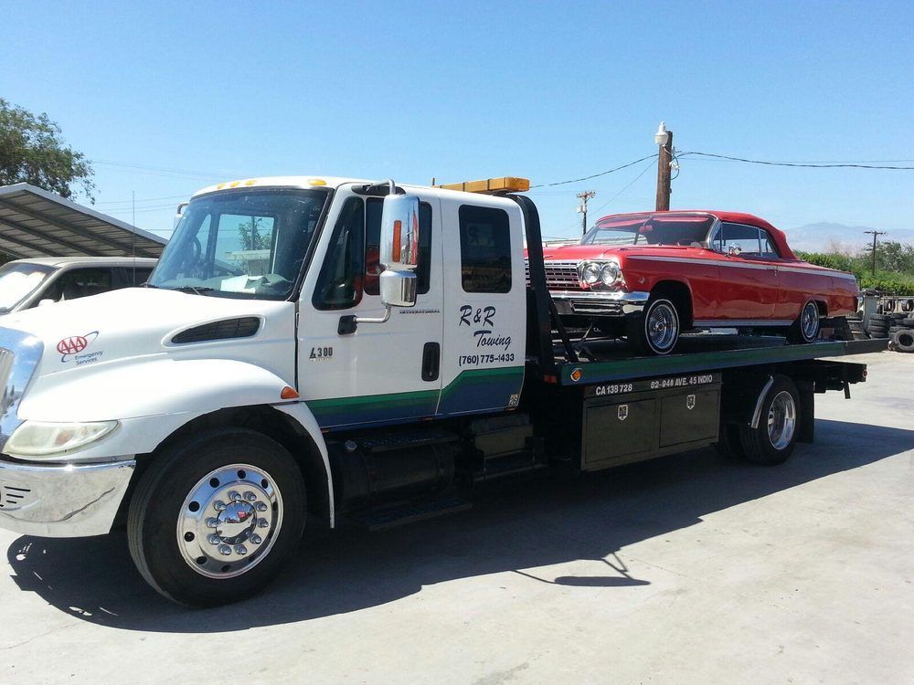 A tow truck with a red car on the back of it