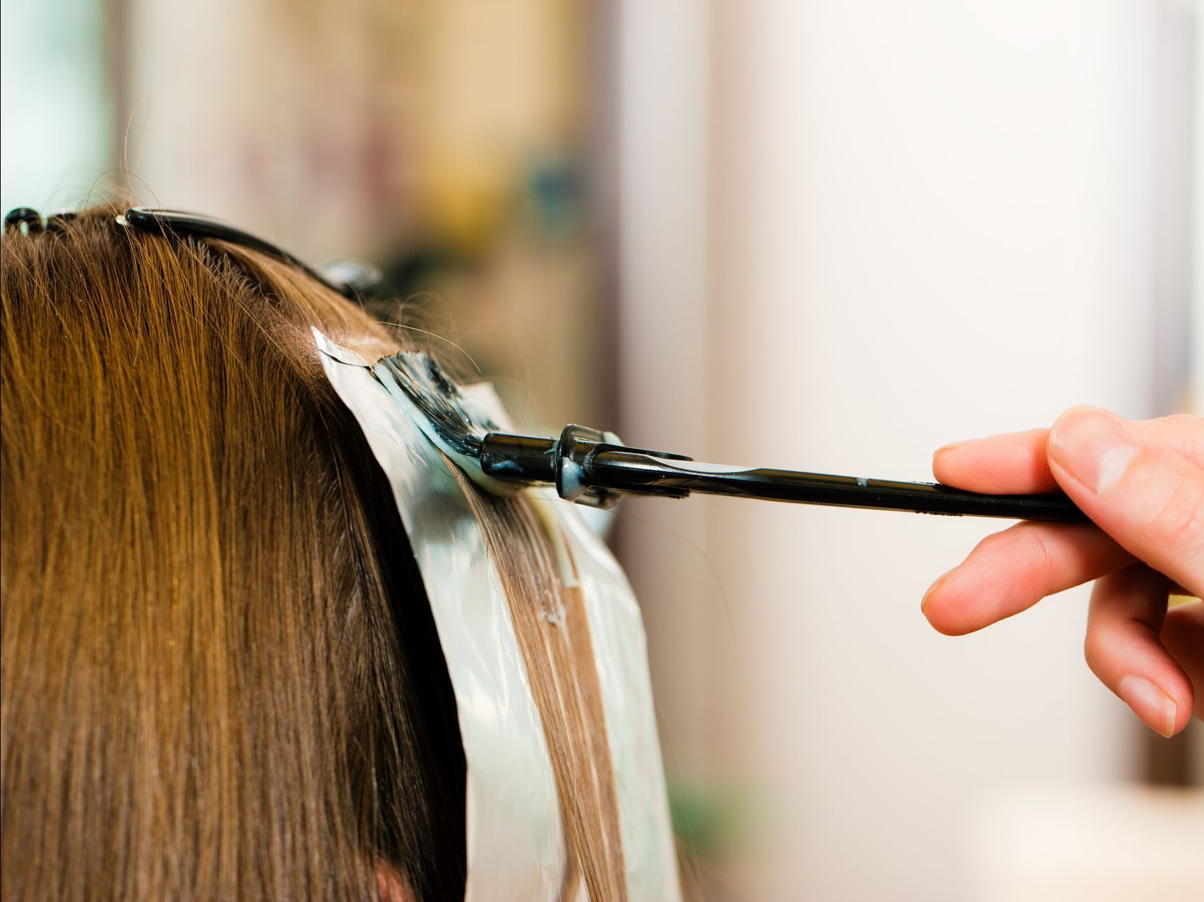 A woman is getting her hair dyed in a salon.