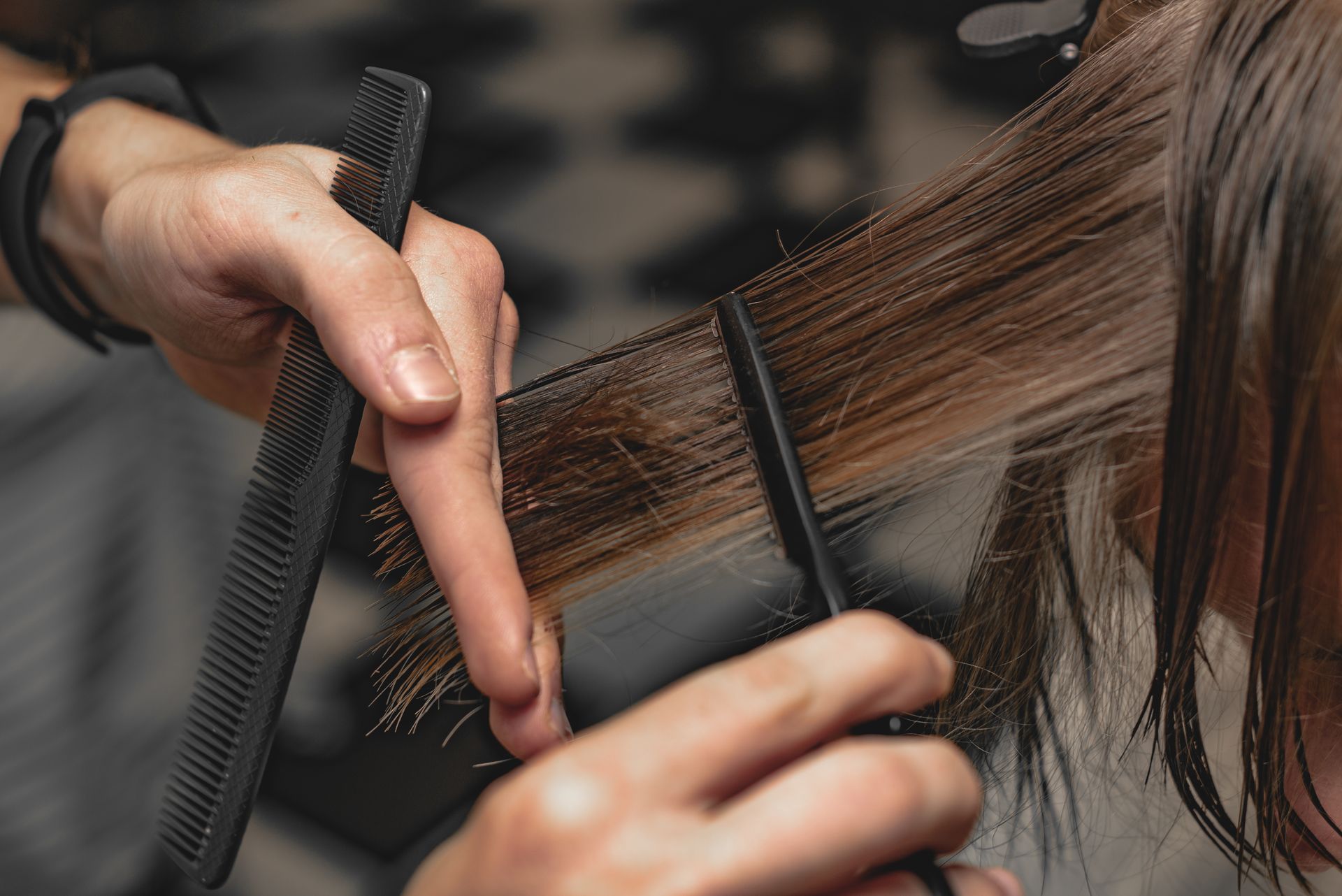 A woman is getting her hair cut by a hairdresser.