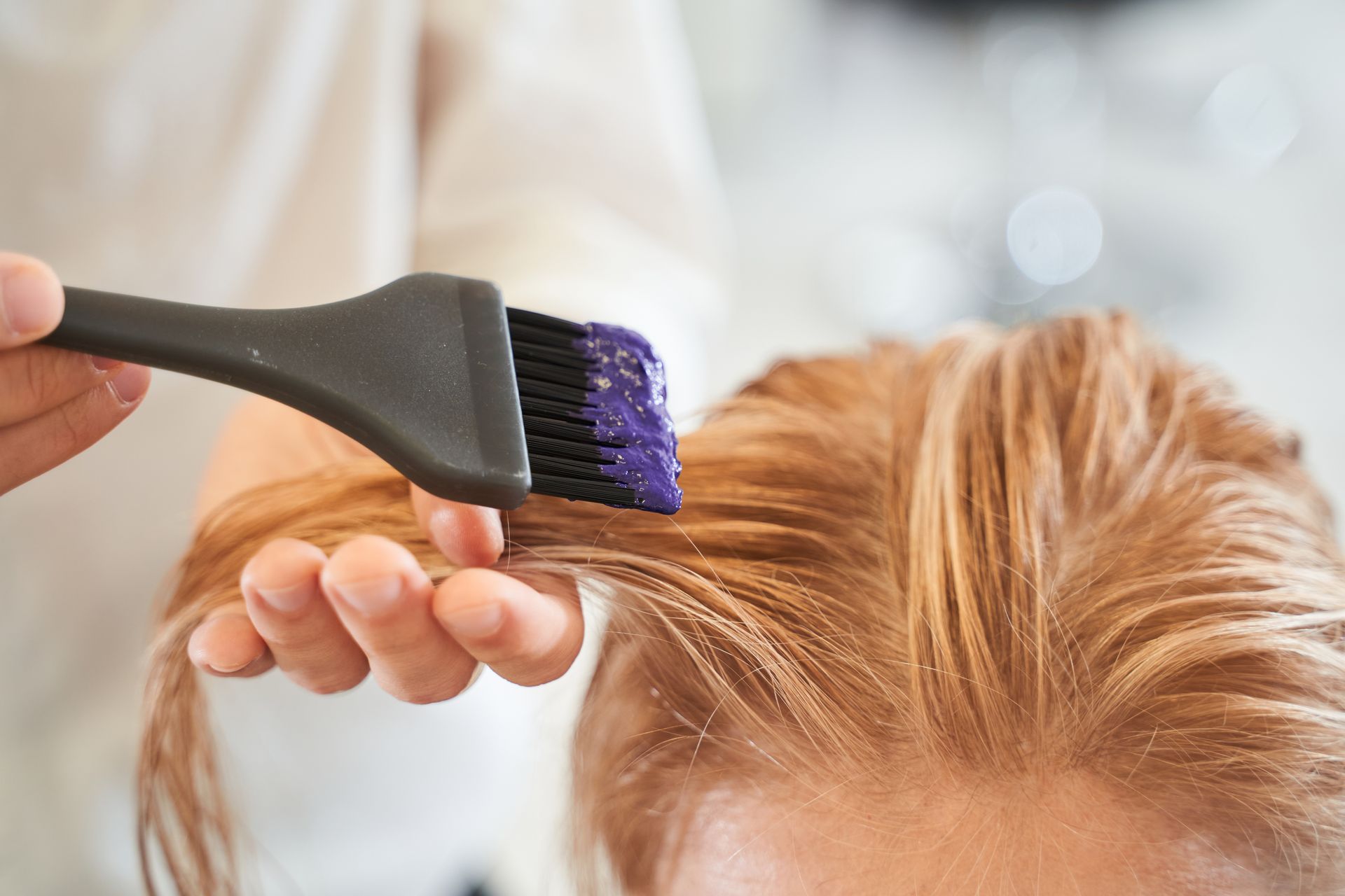 A woman is getting her hair dyed in a salon.