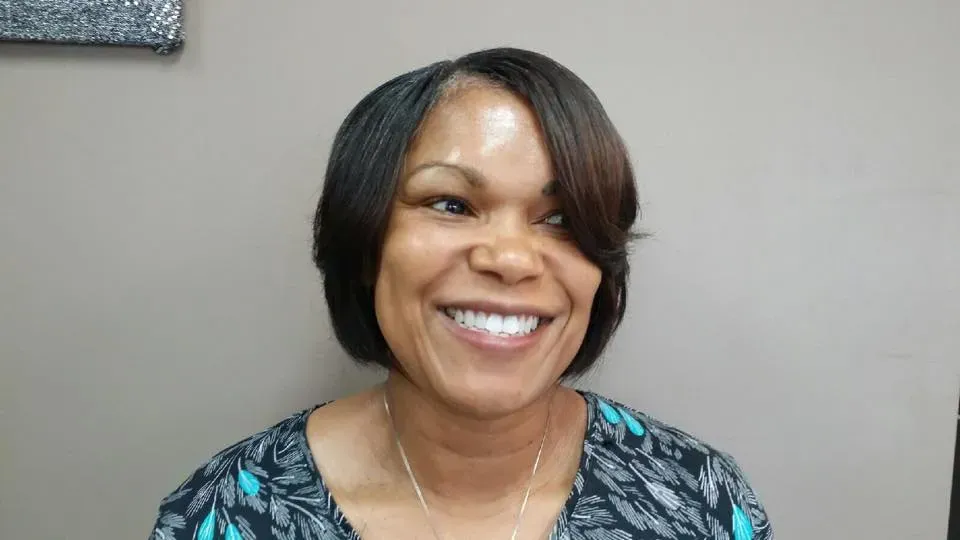 Smiling woman in a patterned top against a plain gray background