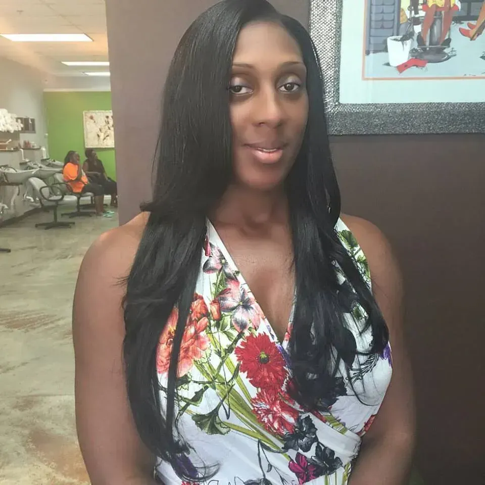 Woman in floral halter dress standing indoors, smiling slightly in a lobby.