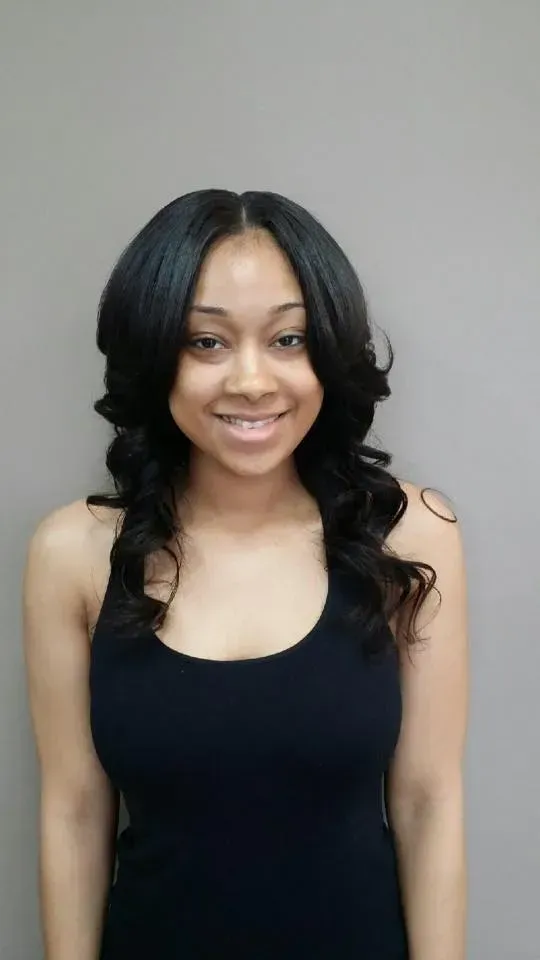 Smiling woman in a black sleeveless top against a plain gray background