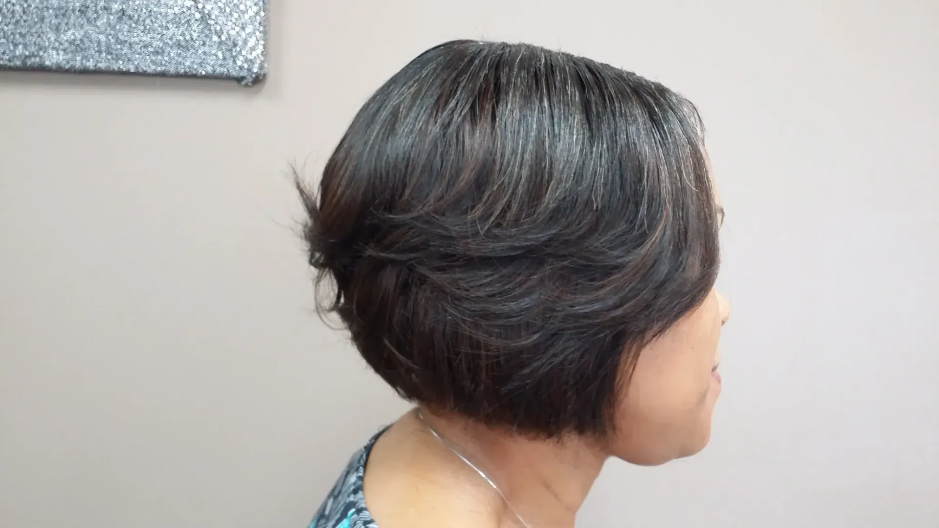 Profile of a person with short dark hair, turned to the right against a plain wall.