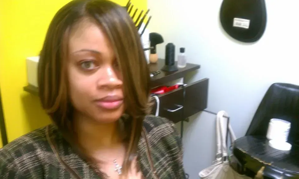 Woman posing in a small room with a desk, chair, and wall-mounted mirror.