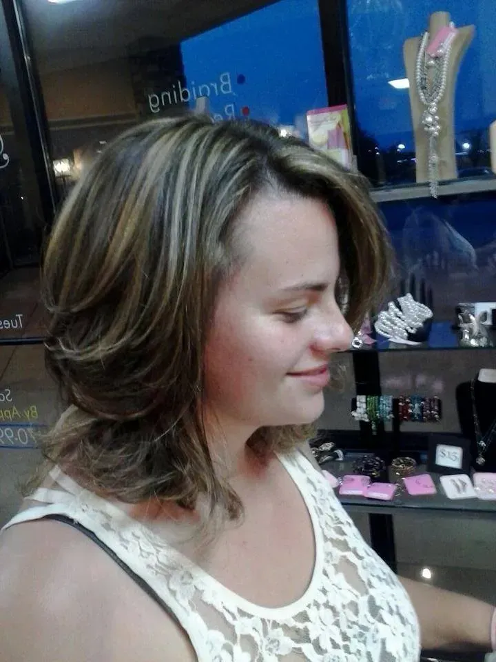 Woman with shoulder-length highlighted hair smiling in a jewelry store display area