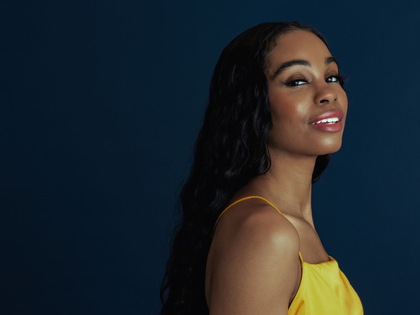Woman in a yellow dress smiling against a dark blue background