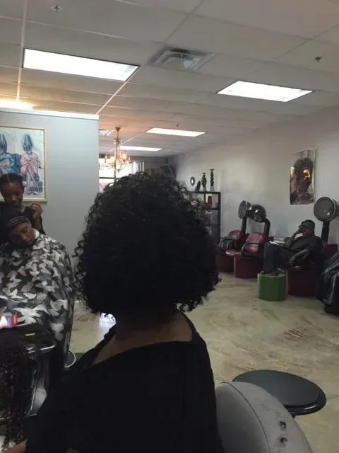 Salon interior with people seated under bright ceiling lights and wall posters.