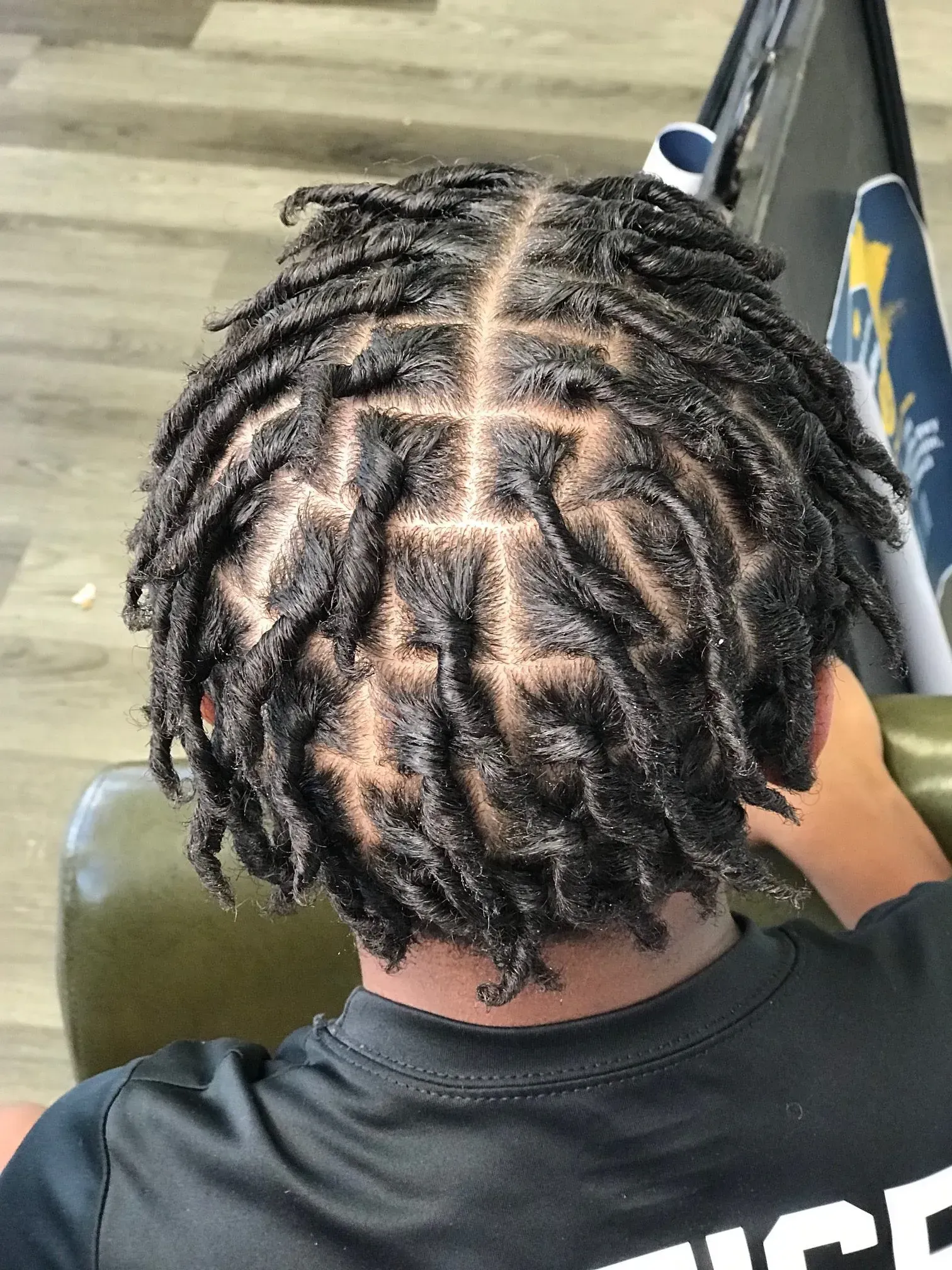 Top view of short twisted braids with a neat center part, sitting in a chair on a wood floor.