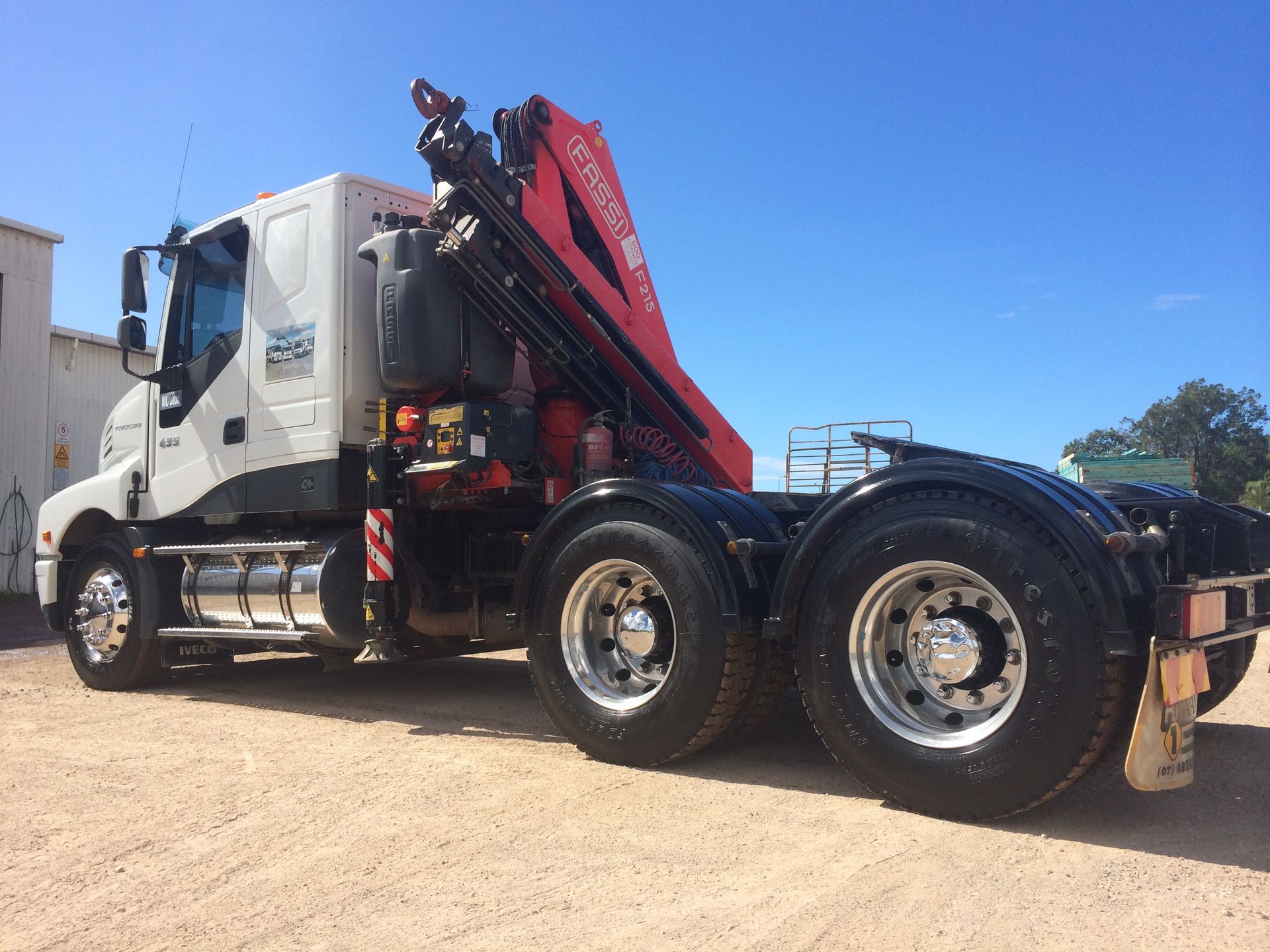 White truck with red crane boom parked on gravel under a clear blue sky — Trucking Crane Trucks in Warana, QLD