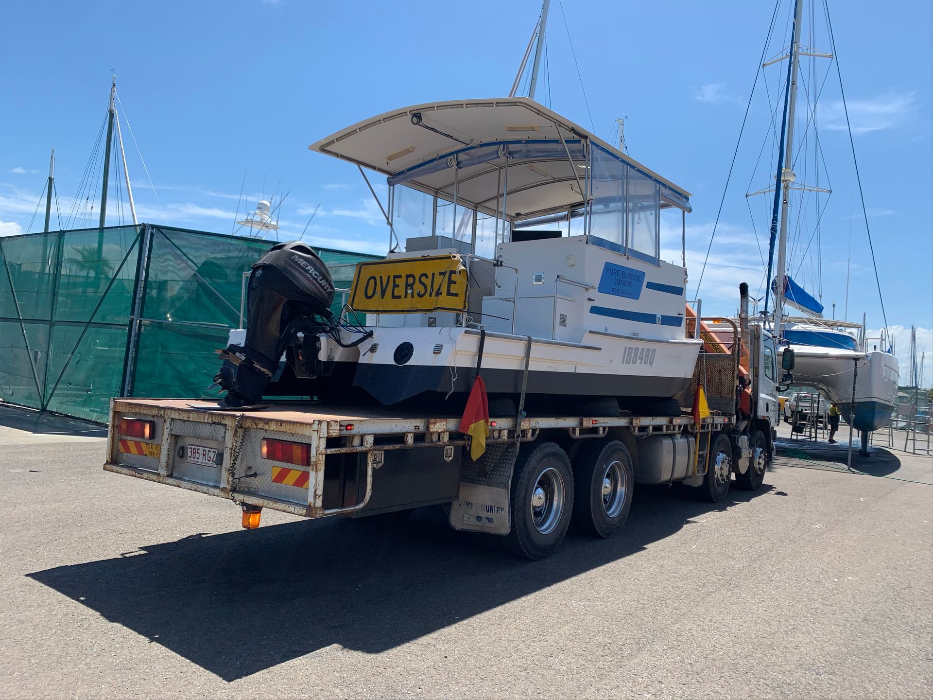 Oversize load on a flatbed trailer, carrying a small boat or cabin structure on a sunny road. — Trucking Crane Trucks in Caboolture, QLD