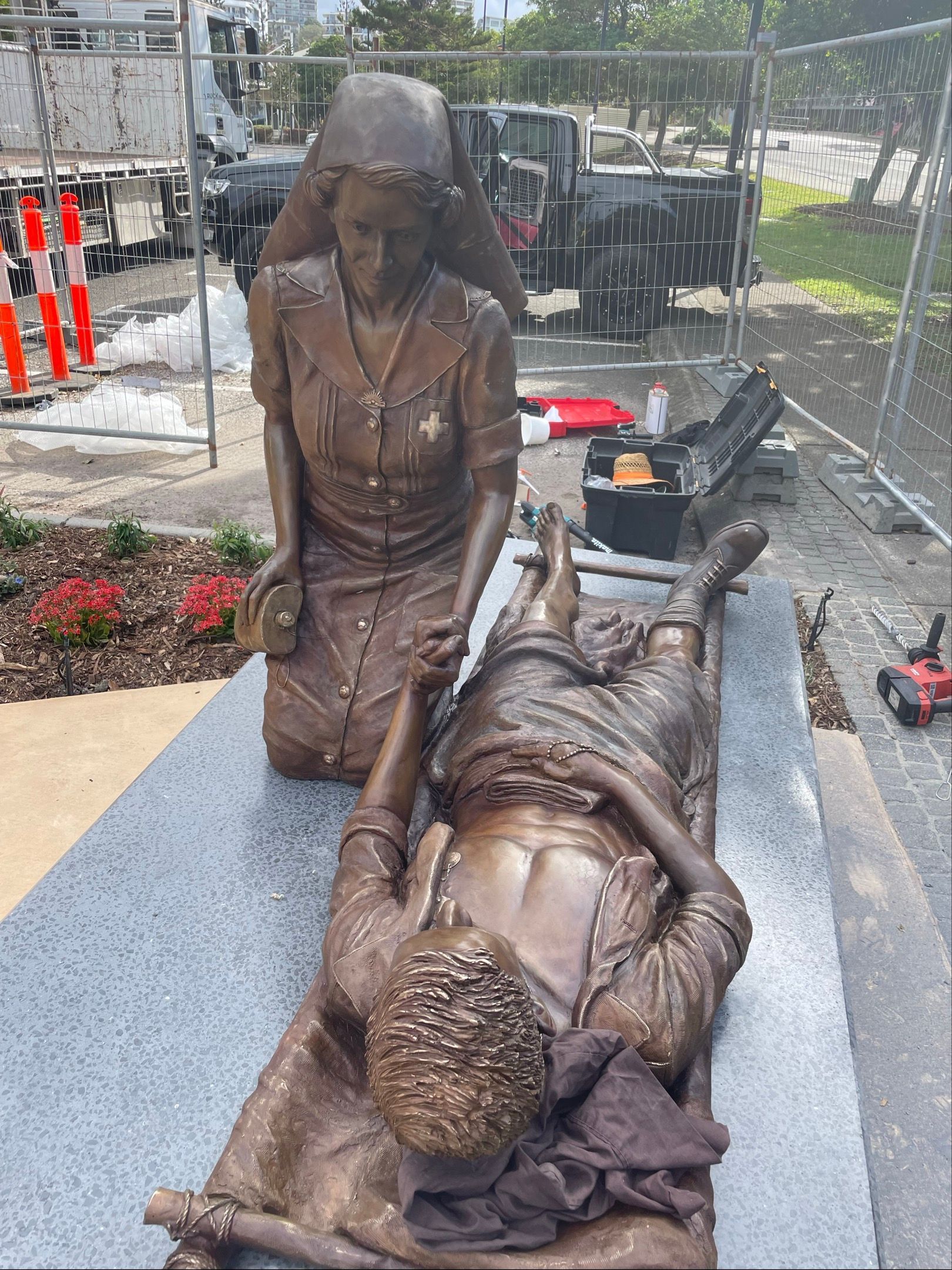 Bronze memorial statue of two people, one kneeling beside another lying on a stone base outdoors. — Trucking Crane Trucks in Caboolture, QLD