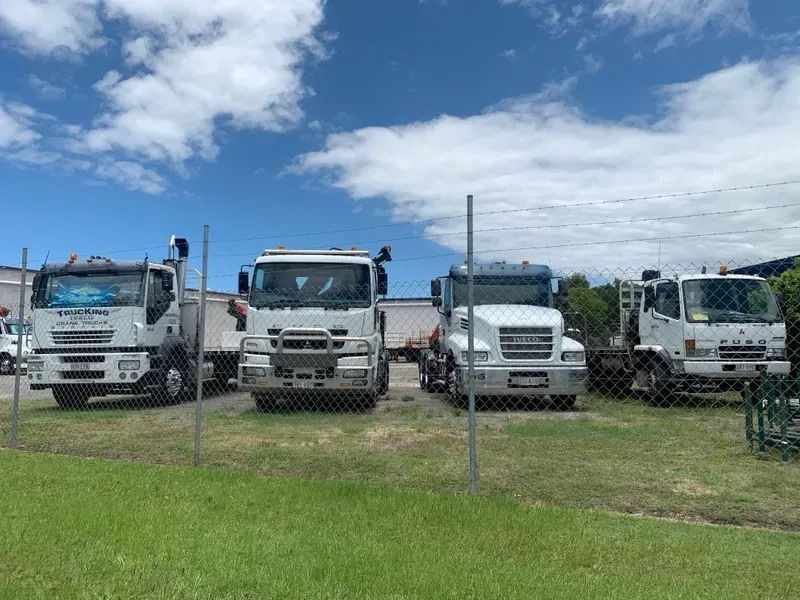 A row of white trucks are parked in a grassy field.