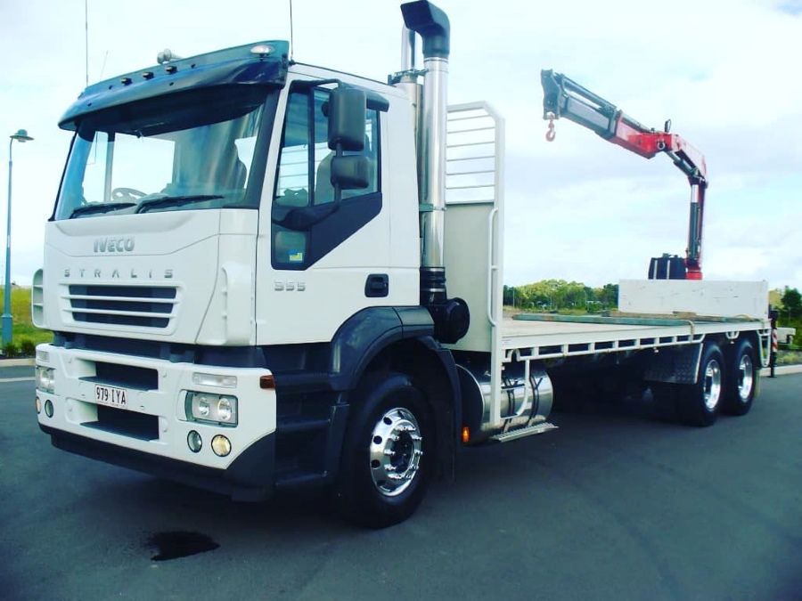 White flatbed truck with a mounted crane parked on a road under a blue sky — Trucking Crane Trucks in Caboolture, QLD