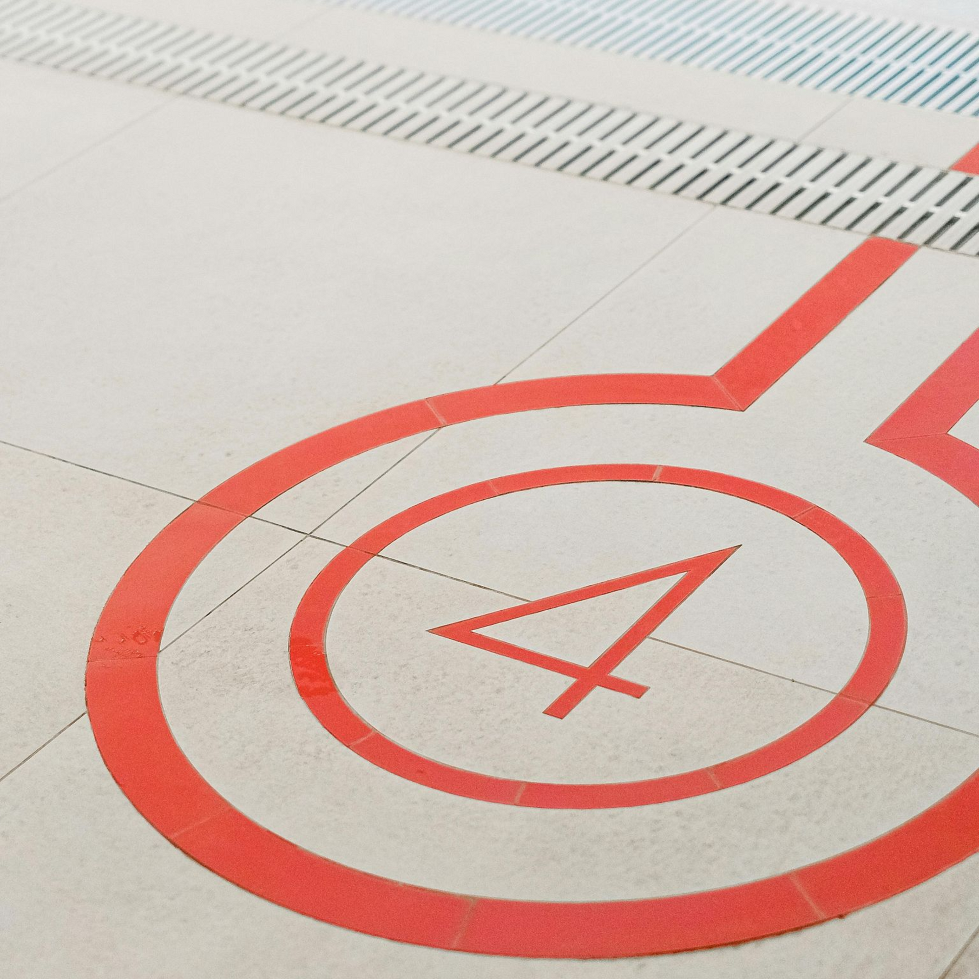 Red painted number 4 within a circle on a light-colored floor, possibly a train platform.