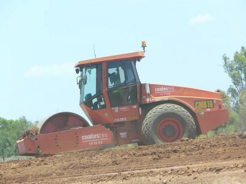 Red Bulldozer Rolling On The Dirty Road — Mike Barlow Earthmoving Pty Ltd in Rockhampton, QLD